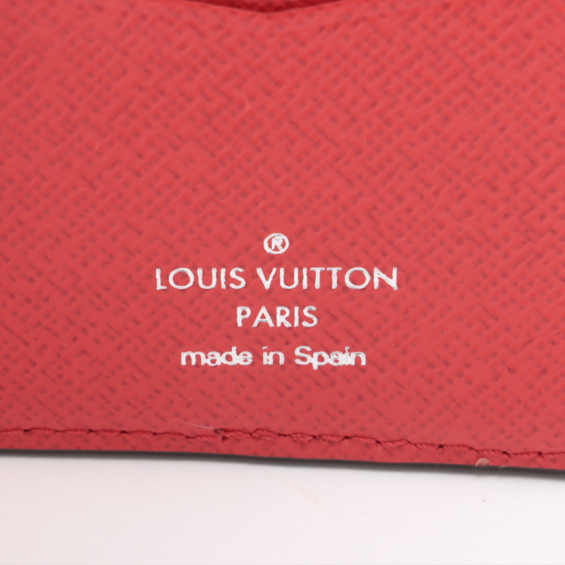 Louis Vuitton logo on a red textured surface with 'made in Spain' text.