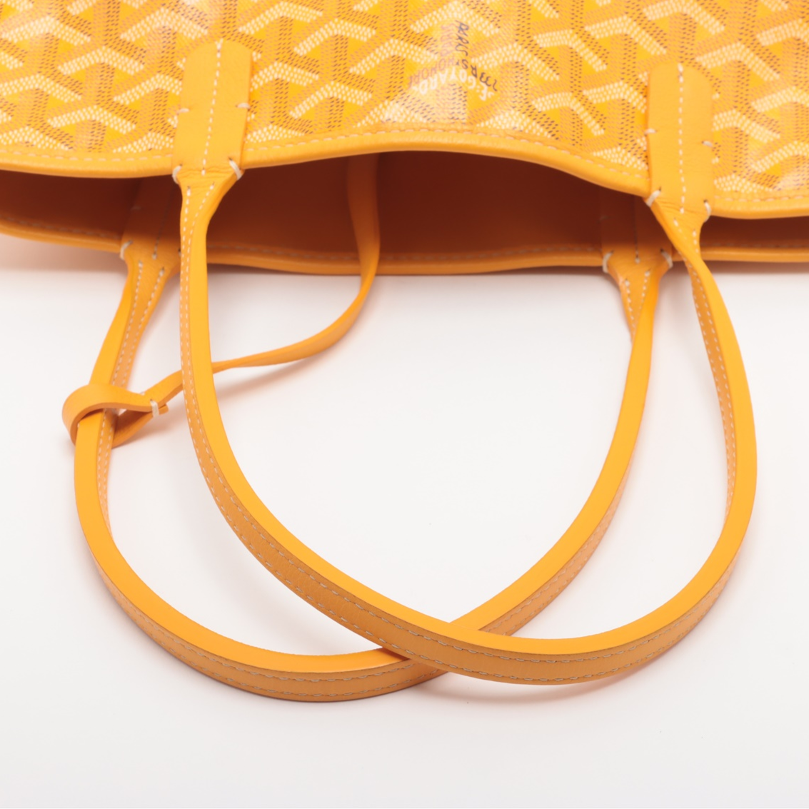 Close-up of a yellow textured handbag with handles on a white background