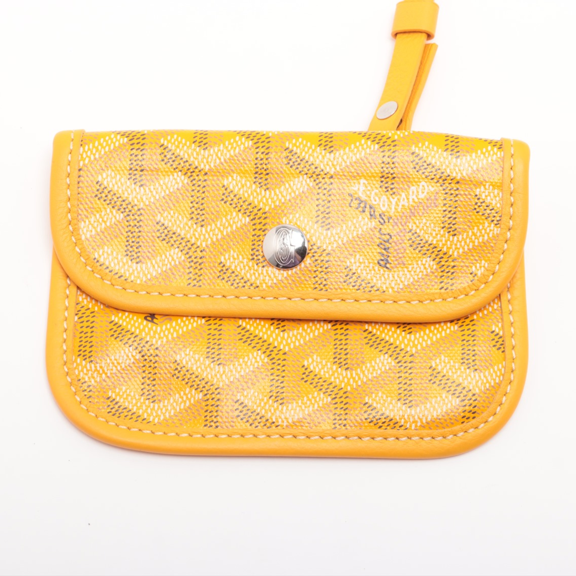 Yellow textured handbag with a silver button on a white background